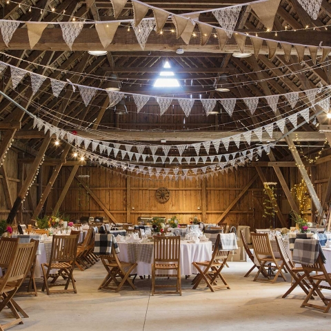Tables and chairs set up in a barn for a wedding